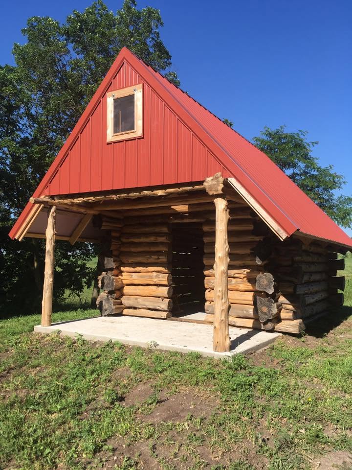 Small cedar cabin with red metal roof and log porch