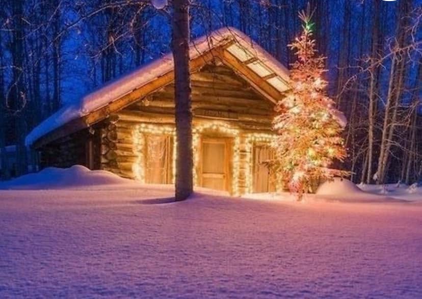 Log cabin in snow with Christmas lights