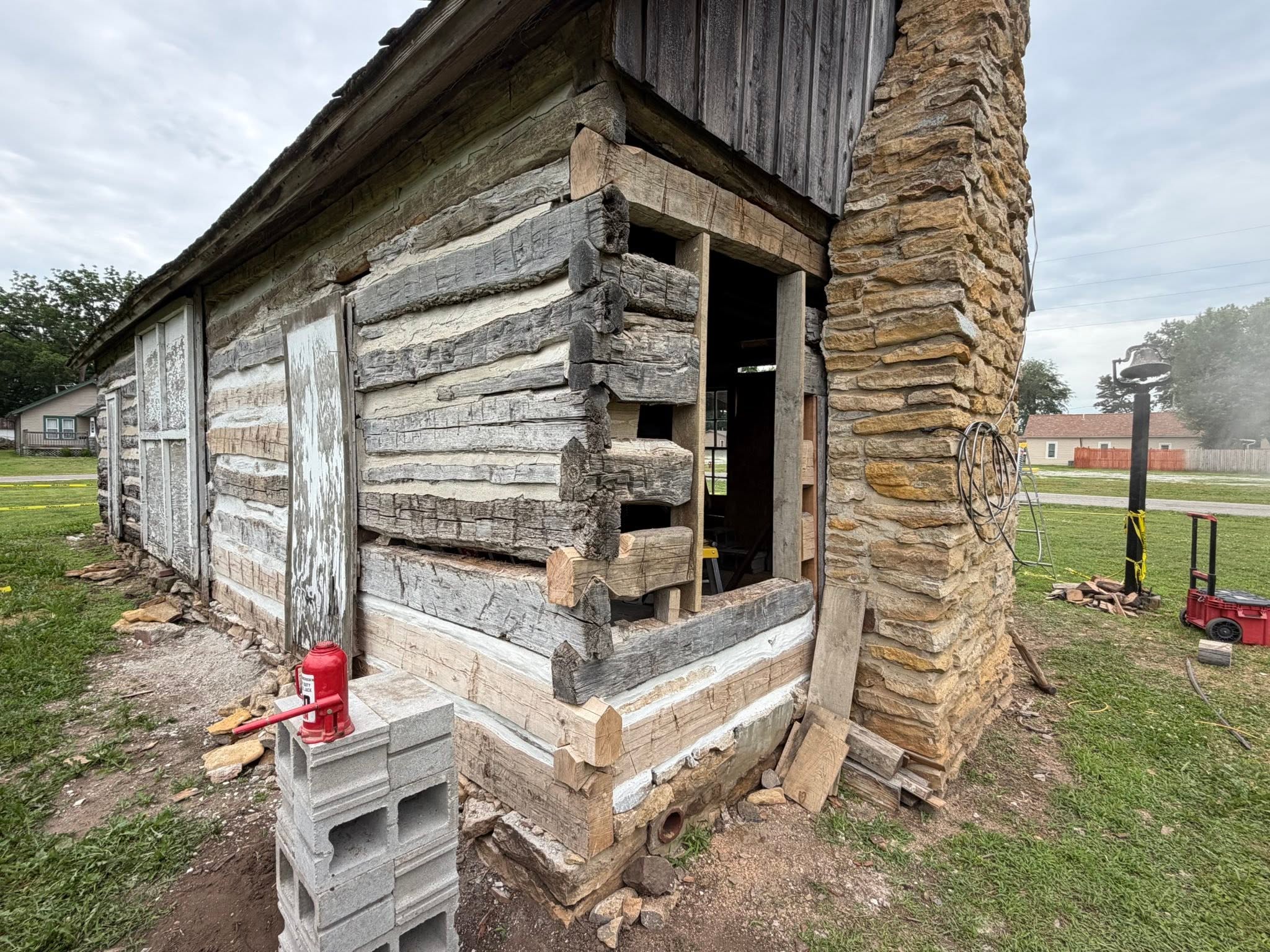 Craftsman hand-fitting repair at the base of a historic log wall